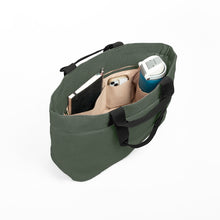 Load image into Gallery viewer, An olive green canvas tote bag shown from an overhead angle, filled with a notebook, a smartphone, and a blue water bottle, on a clean white background.
