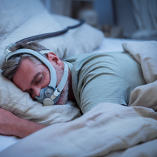 Load image into Gallery viewer, Man sleeping with a CPAP mask in a bedroom setting
